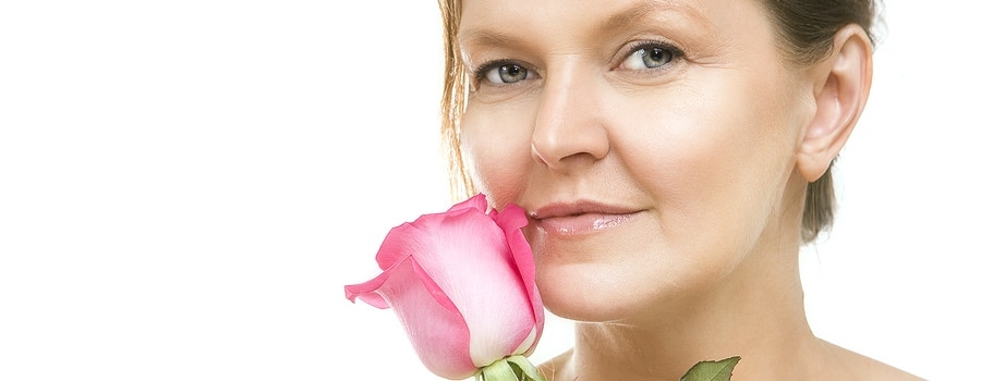 Attractive Mid Adult Woman, Female Face Of Beautiful Caucasian With A Pink Rose beautiful caucasian woman looking at camera mid adult female face - Portrait of happy aged woman over white background