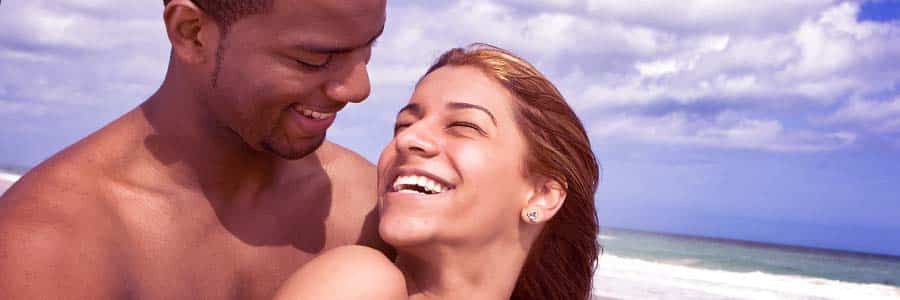 couple on beach smiling while looking at each other